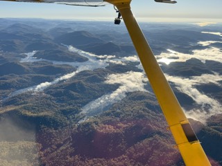 Ridges and a lake under the wing strut, with low cloud lying in the valleys